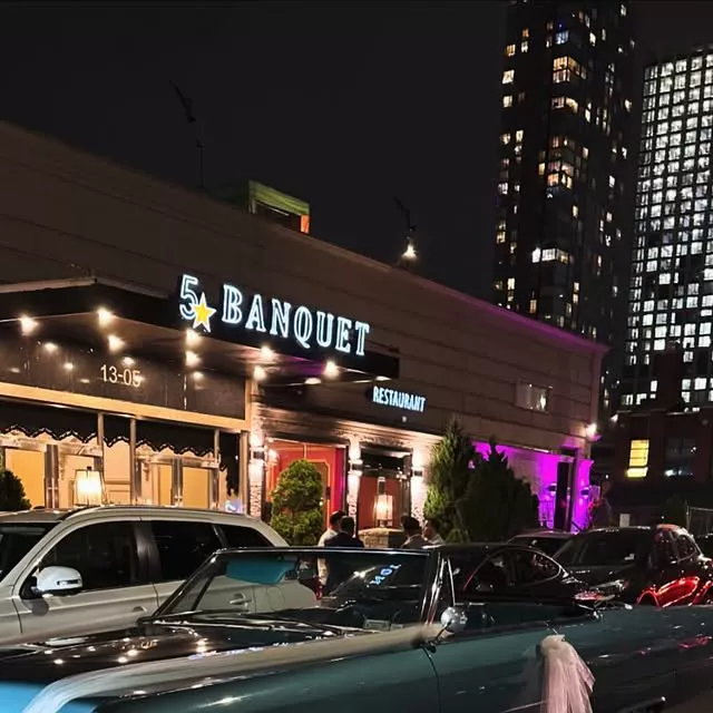 5 Star Banquet Hall lit up at night, with a ribbon-trimmed vintage convertible out front