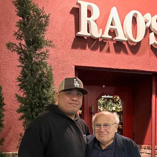 Two men posing outside the red facade of Rao’s in Hollywood