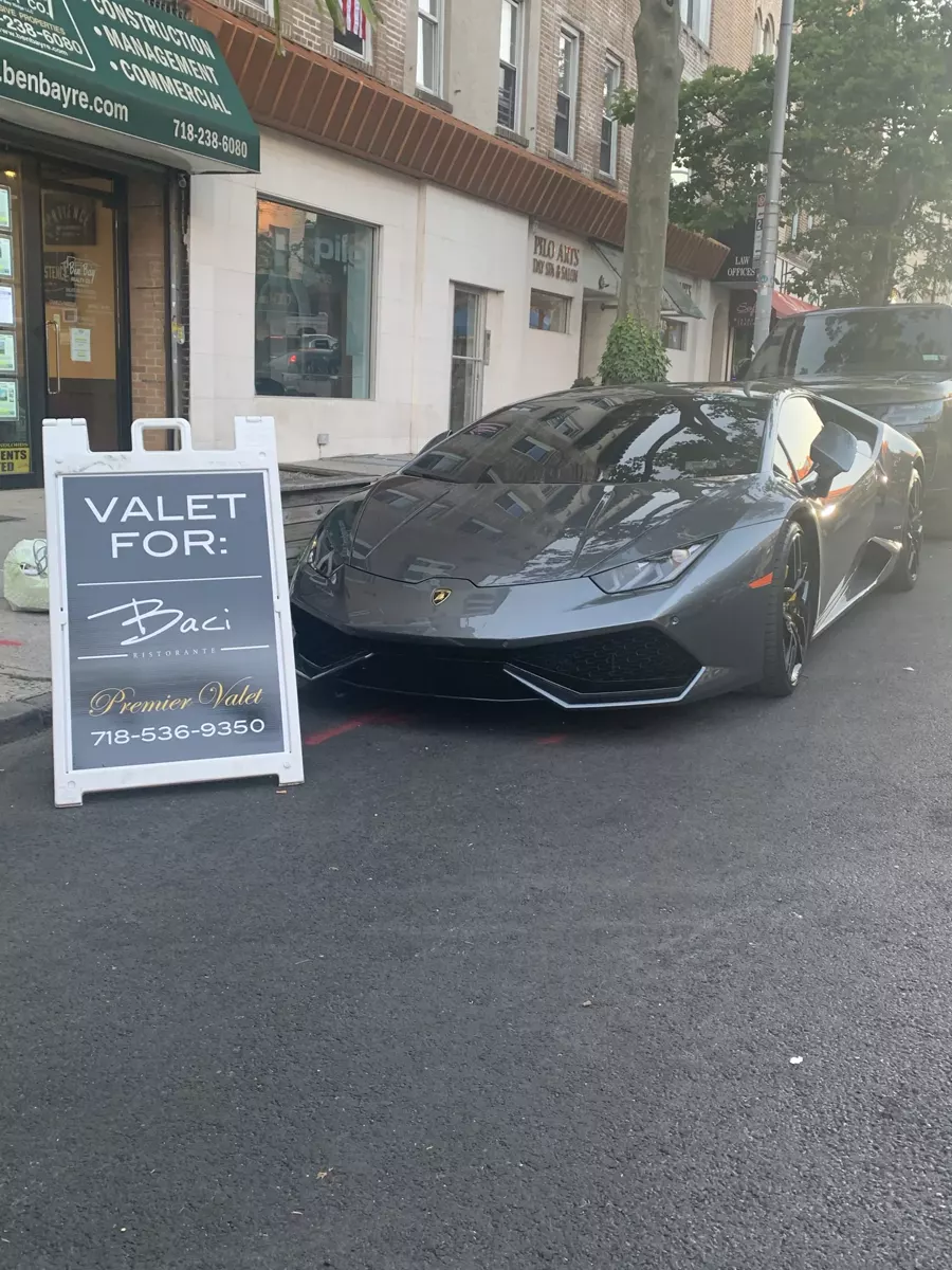 Gray Lamborghini parked at the curb beside a Premier Valet sign for Baci Ristorante