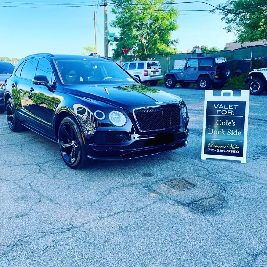 Black Bentley SUV in a parking lot beside a Premier Valet sign reading Valet For: Cole's Dock Side