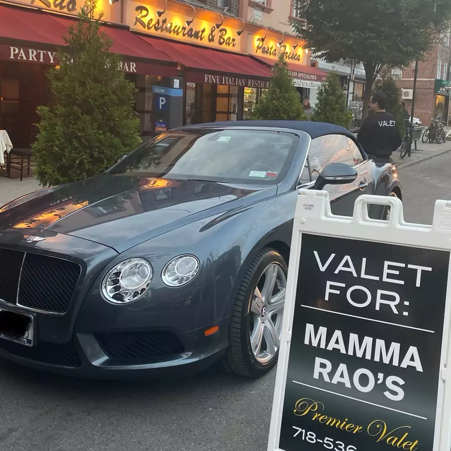 Blue-gray Bentley convertible beside a Valet For: Mamma Rao's sign outside a restaurant with red awnings