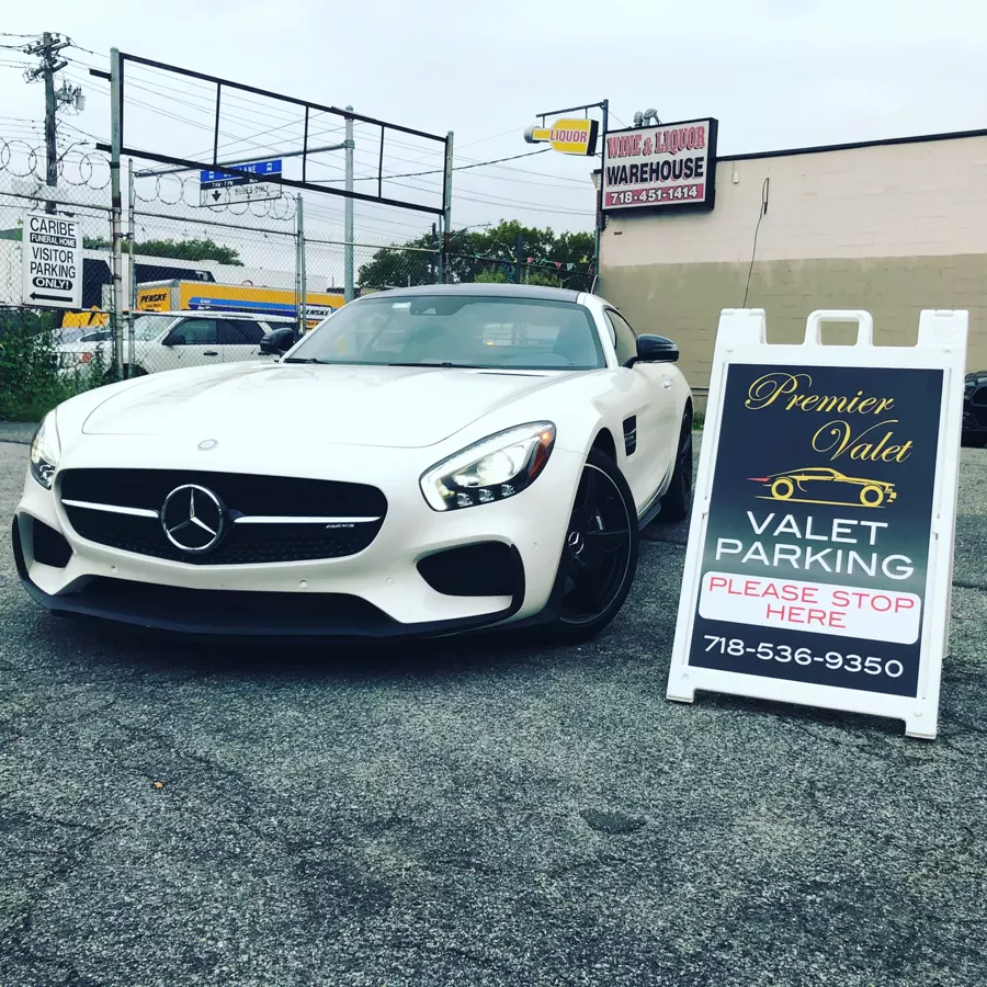 White Mercedes-AMG coupe parked beside a Premier Valet sign reading Valet Parking, Please Stop Here