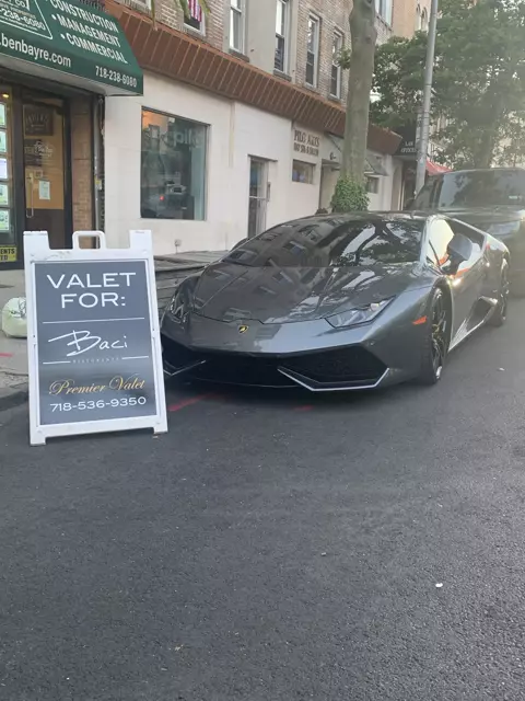Gray Lamborghini parked at the curb beside a Premier Valet sign for Baci Ristorante