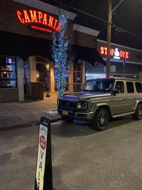 Gray Mercedes G-Class parked at night outside Campania Coal Fired Pizza, valet marker in front