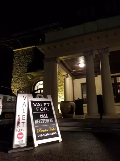 Two valet signs at night in front of a columned portico, one for Casa Belvedere