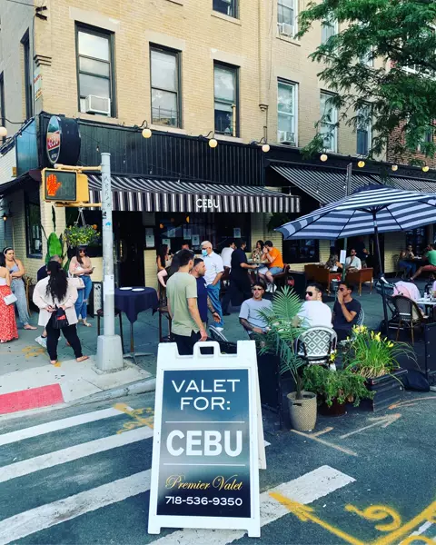 Premier Valet sign for Cebu in a crosswalk outside the restaurant, diners at outdoor tables