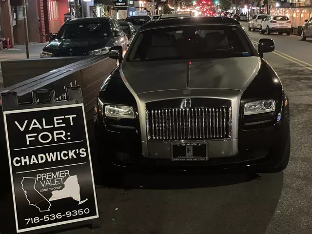 Premier Valet sign for Chadwick's beside a black and silver Rolls-Royce parked on a street at night
