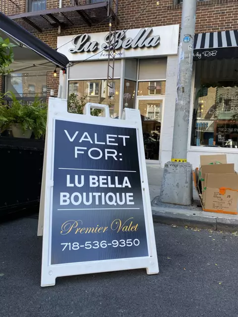 Premier Valet sign reading Valet For: Lu Bella Boutique on the street in front of the Lu Bella storefront
