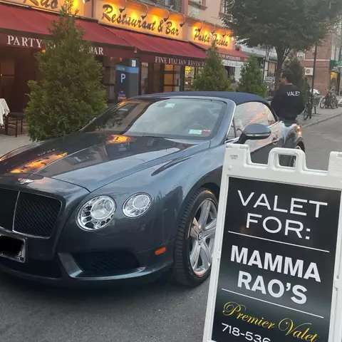 Blue-gray Bentley convertible beside a Valet For: Mamma Rao's sign outside a restaurant with red awnings