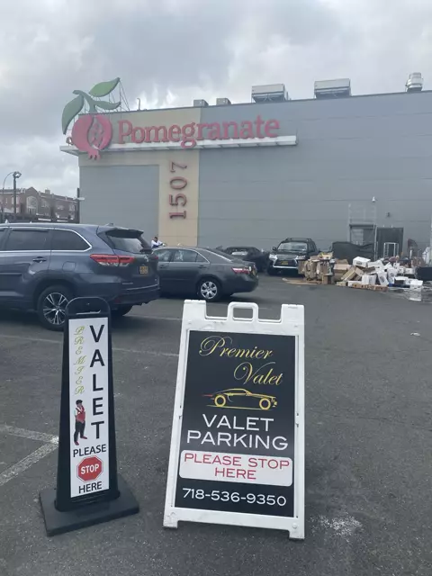 Premier Valet parking signs in a lot outside a building with a Pomegranate sign on a cloudy day