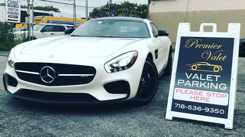 White Mercedes-AMG coupe parked beside a Premier Valet sign reading Valet Parking, Please Stop Here