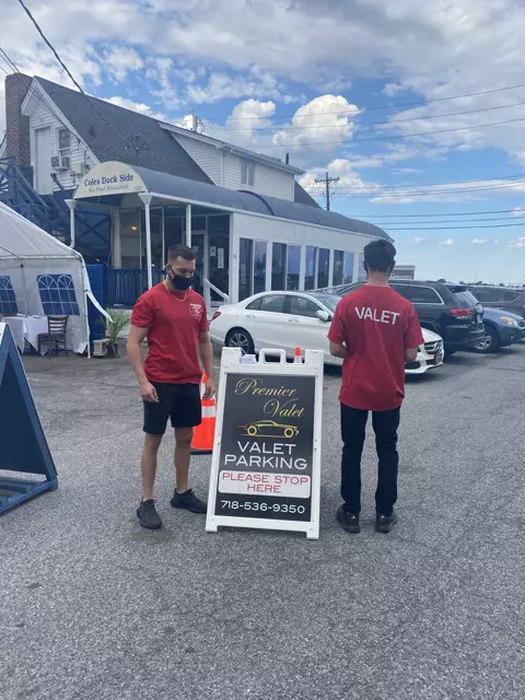 Two attendants in red Premier Valet shirts by the valet sign at Coles Dock Side Sea Food Restaurant