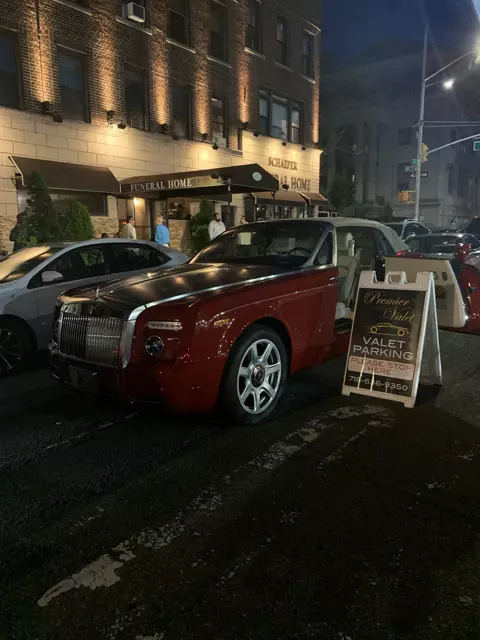 Red and black Rolls-Royce beside a Premier Valet sign outside Schaefer Funeral Home