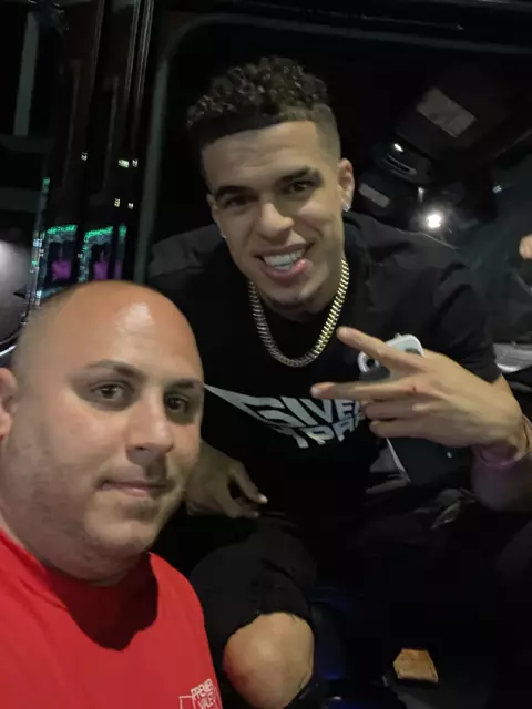 Selfie of a man in a red Premier Valet T-shirt with a smiling man inside a vehicle lit by LED trim